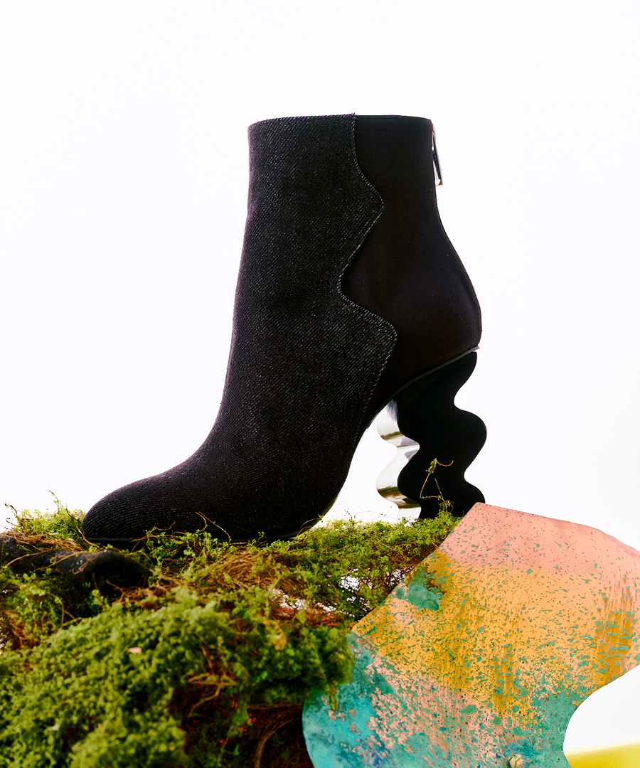 Black INES denim ankle boot on a textured surface with a colorful abstract design