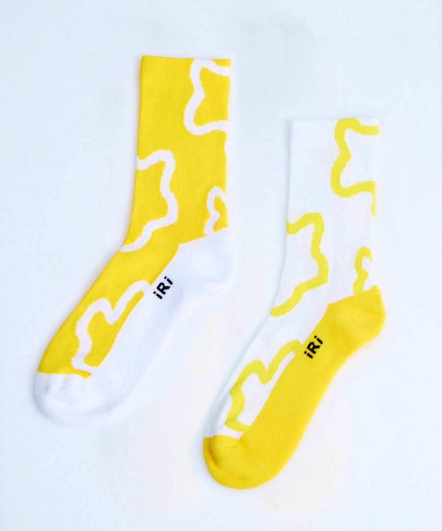 Yellow and white socks with iRi iconic abstract patterns on a pale grey background