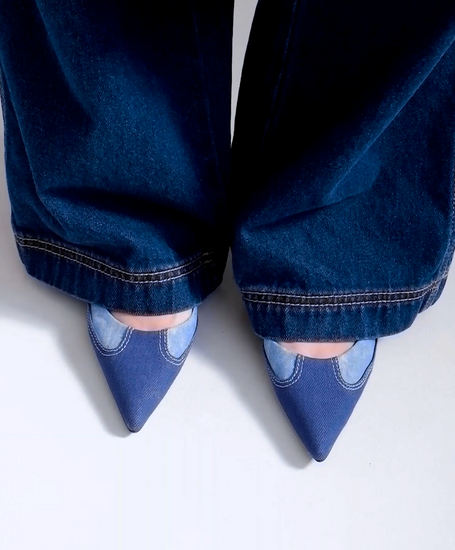 A model walking in ONEL Blue Pointed Toe Pumps, styled with double denim looks (asymmetrical denim skirt over blue jeans)
